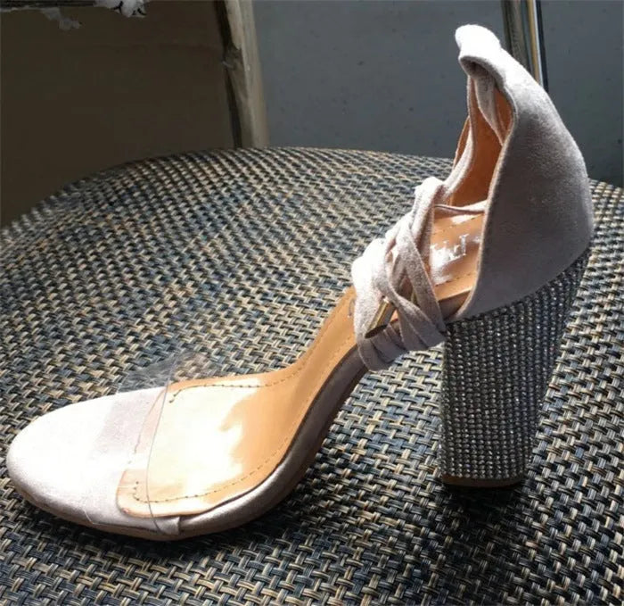 Women's black and gold pointed toe plastic high heels on a plain background.