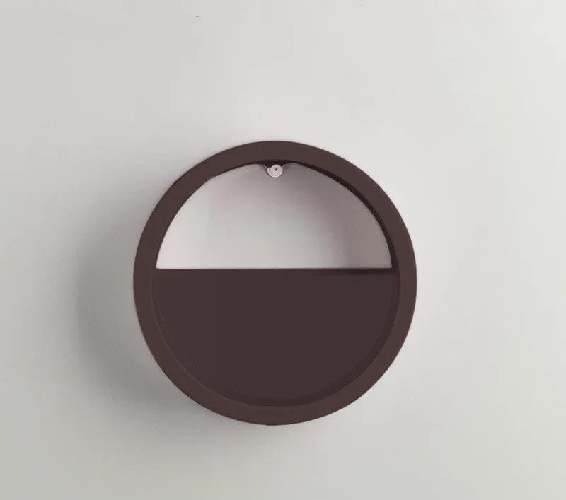 Round iron wall vase in black hanging on a wall with a succulent plant inside