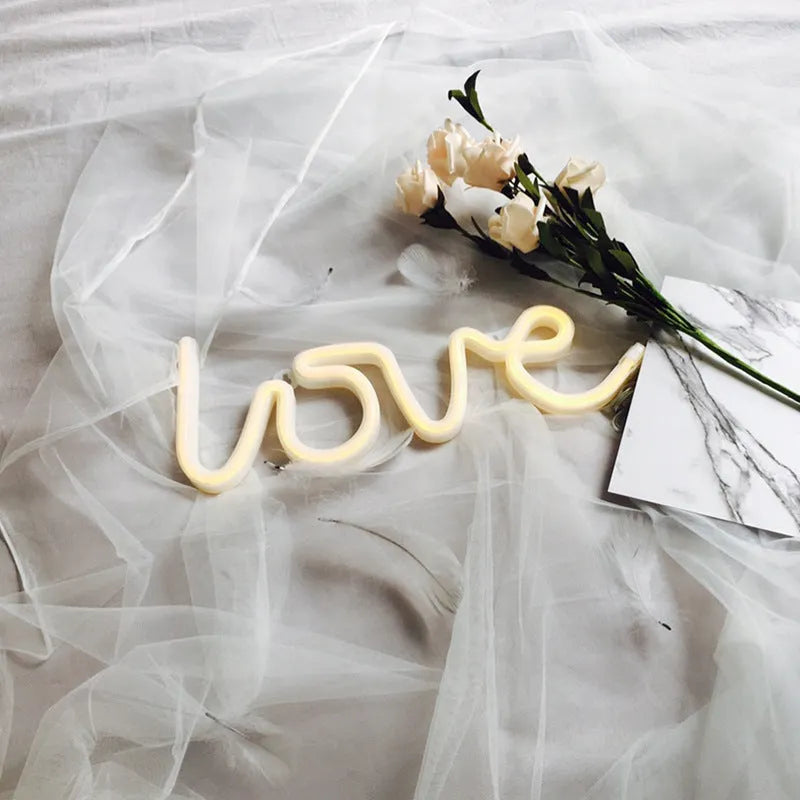 Pink Love-shaped LED neon sign light on a table with battery and USB power options