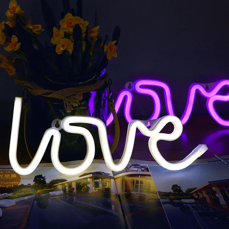 Pink Love-shaped LED neon sign light on a table with battery and USB power options