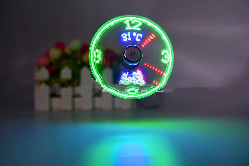 Silver USB clock temperature fan with LED display, soft plastic blades, and flexible metal neck on a desk