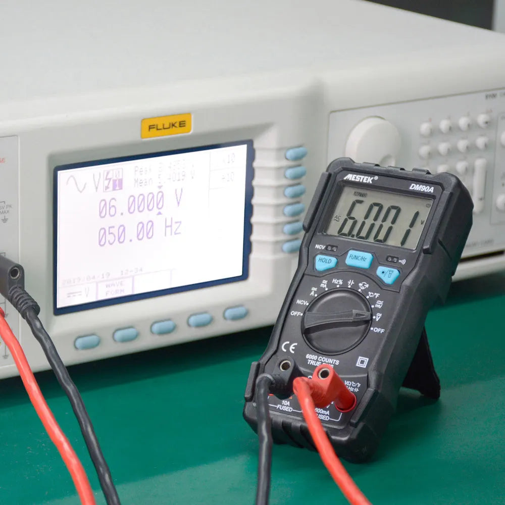 DM90A digital multimeter with display showing readings, test leads, and thermocouple probe on a workbench.