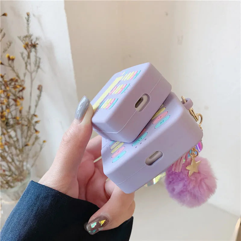 Purple silicone protective case for Apple AirPods with a small furry purple pendant attached.