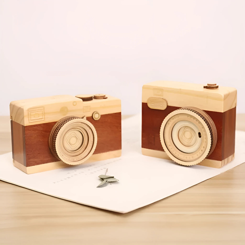 Pine wood camera-shaped music box with rotating mechanism on a wooden surface.