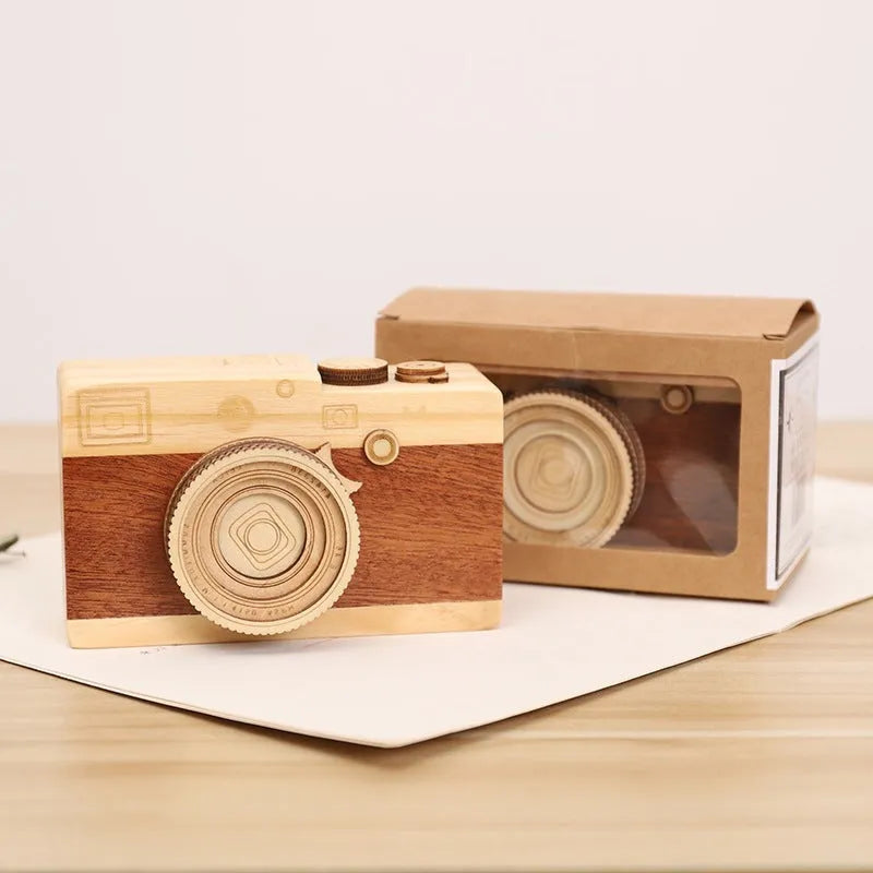 Pine wood camera-shaped music box with rotating mechanism on a wooden surface.