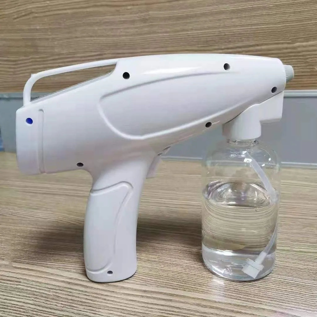 White cordless handheld disinfectant spray gun with USB-C charging port and bottle attached.