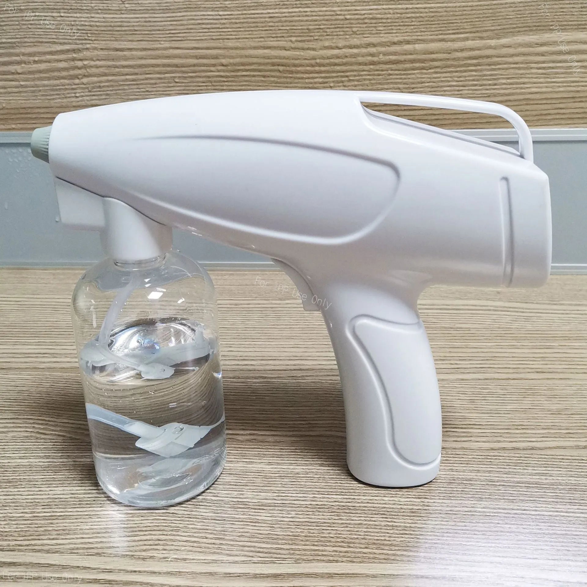 White cordless handheld disinfectant spray gun with USB-C charging port and bottle attached.