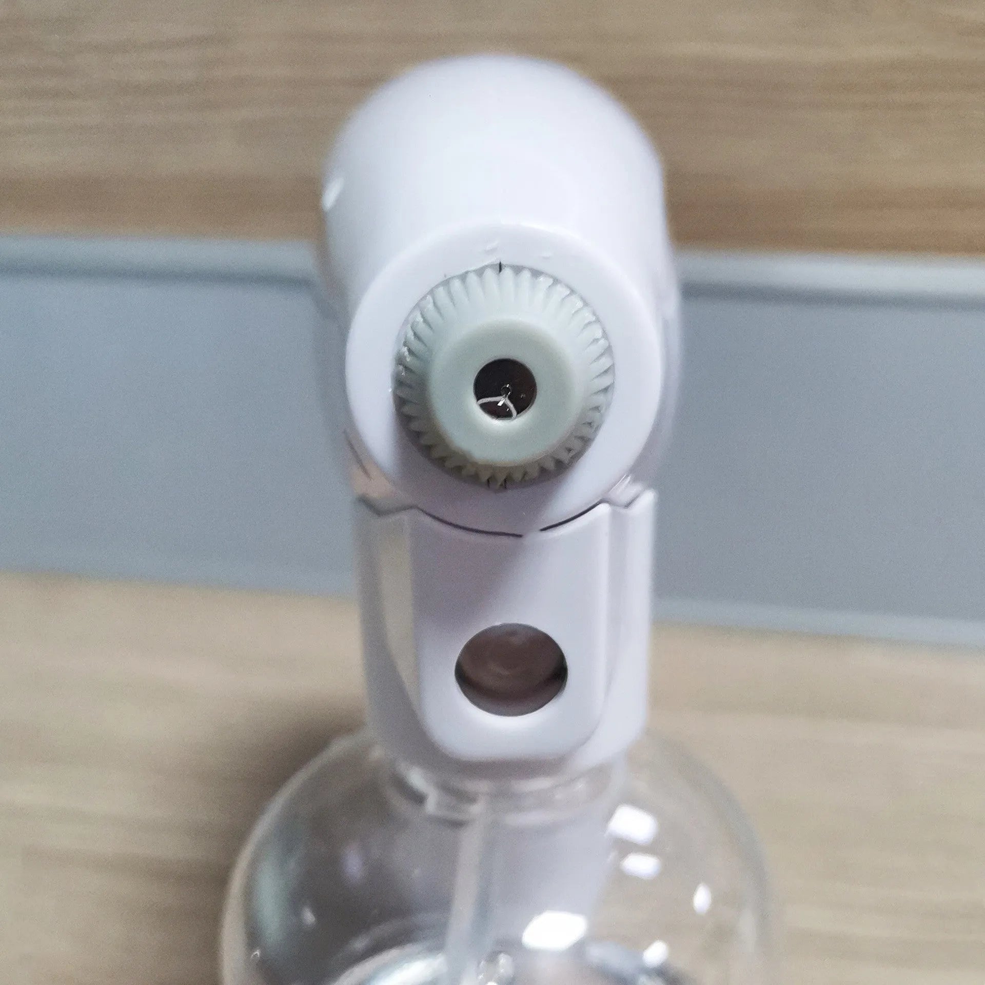 White cordless handheld disinfectant spray gun with USB-C charging port and bottle attached.
