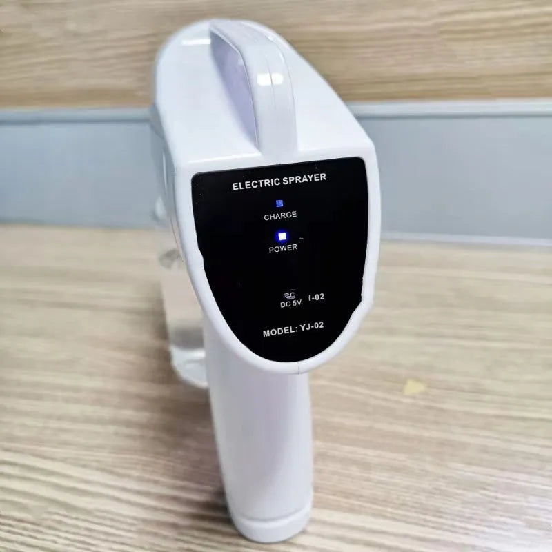White cordless handheld disinfectant spray gun with USB-C charging port and bottle attached.