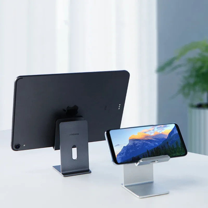 Dark grey alloy mobile phone holder holding a smartphone on a desktop.