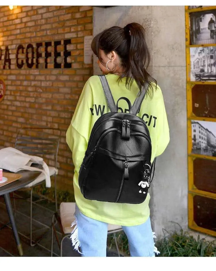 Black soft PU leather backpack with double straps and a zipper opening, showing its medium size.