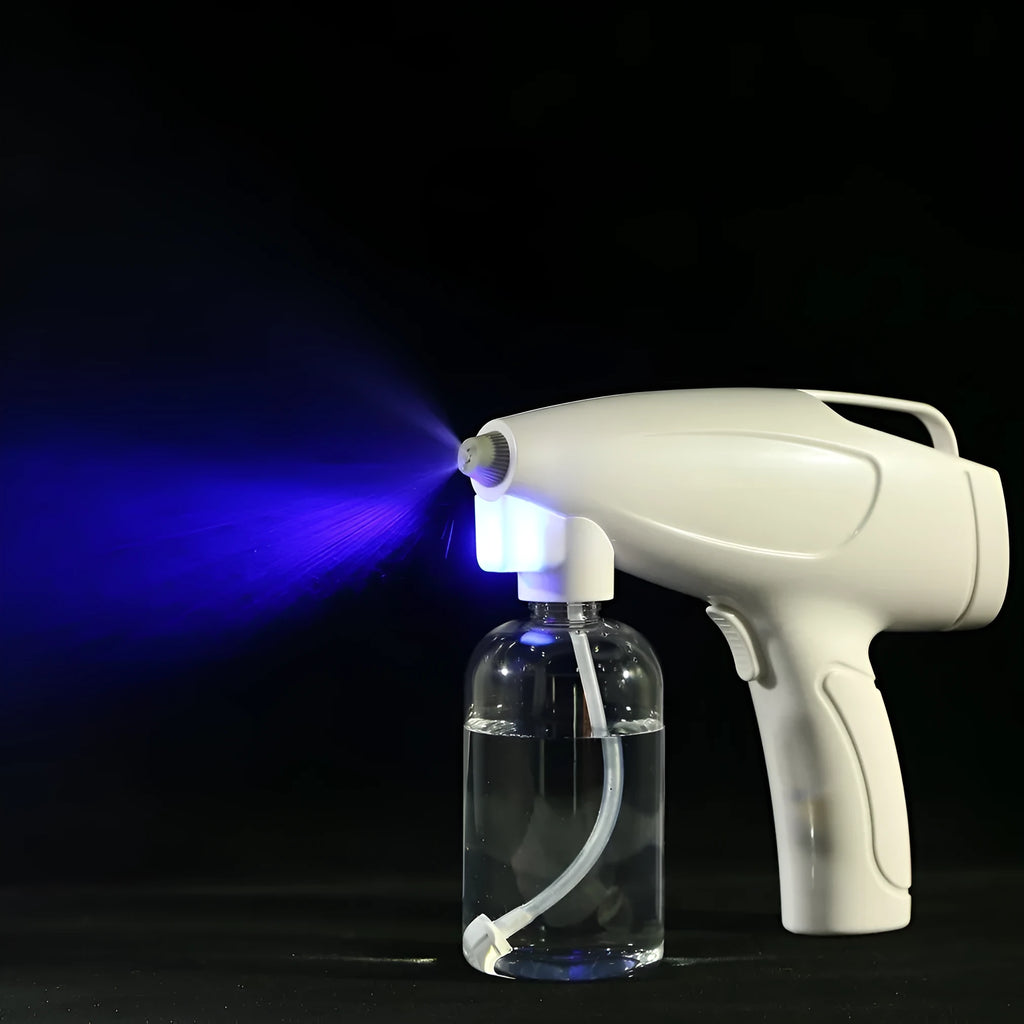 White cordless handheld disinfectant spray gun with USB-C charging port and bottle attached.