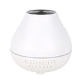 White circular Bluetooth humidifier and aroma diffuser with night light on a wooden surface.