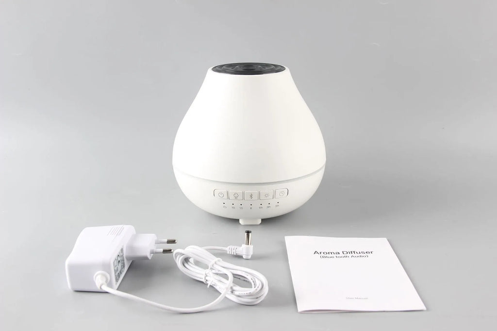 White circular Bluetooth humidifier and aroma diffuser with night light on a wooden surface.