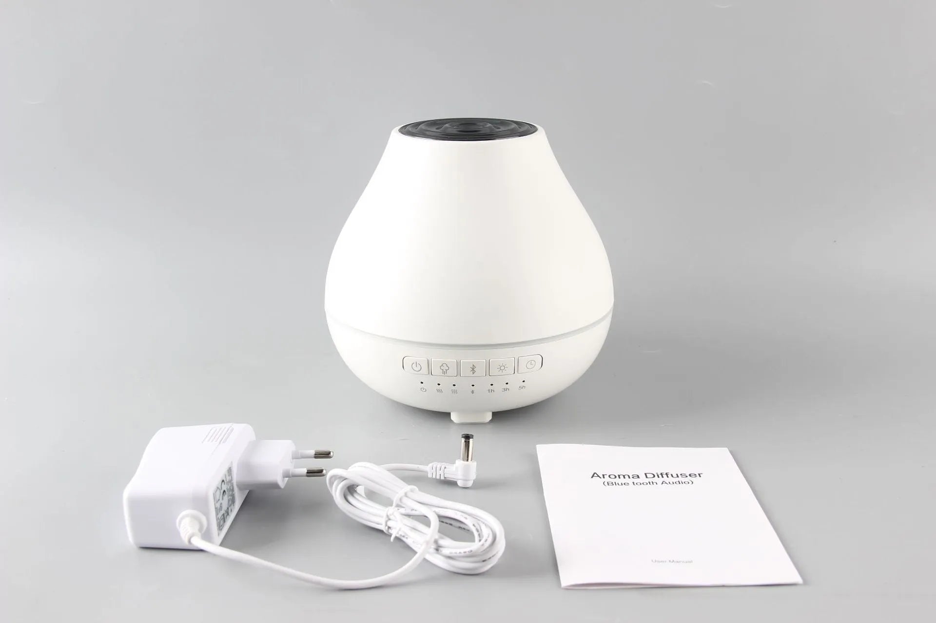 White circular Bluetooth humidifier and aroma diffuser with night light on a wooden surface.