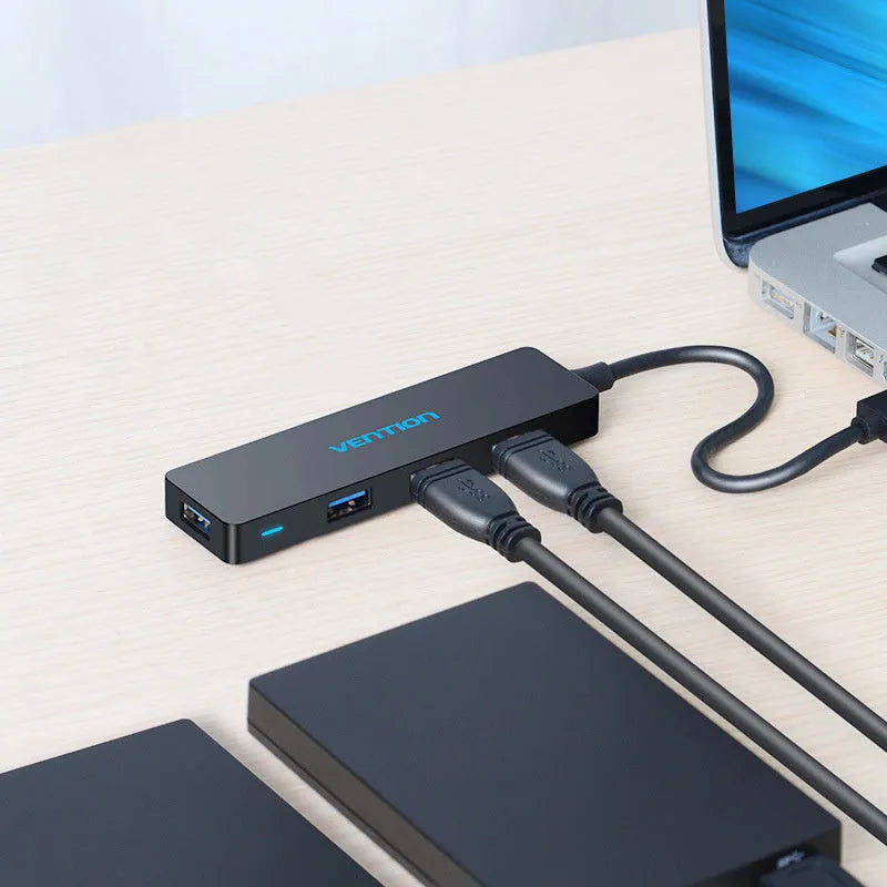 Black four-port USB 3.0 hub with a short attached cable on a desk