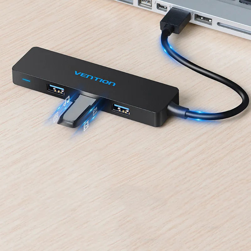 Black four-port USB 3.0 hub with a short attached cable on a desk