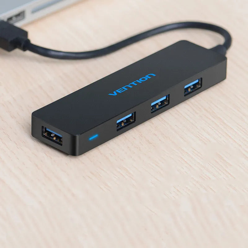 Black four-port USB 3.0 hub with a short attached cable on a desk