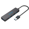 Black four-port USB 3.0 hub with a short attached cable on a desk