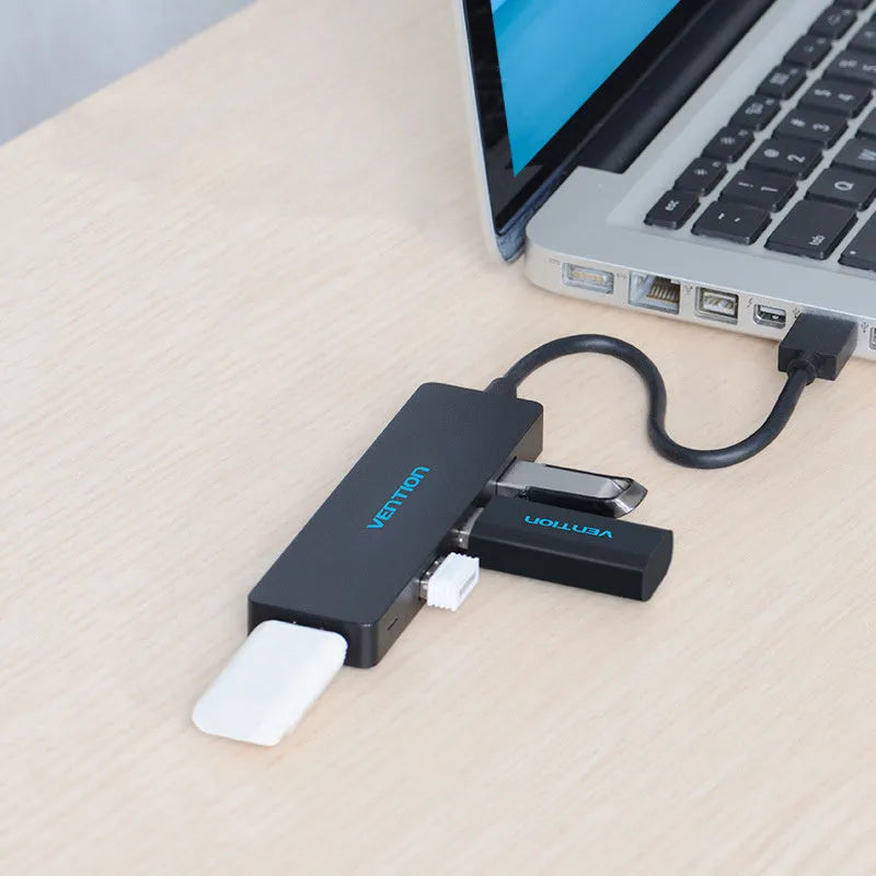 Black four-port USB 3.0 hub with a short attached cable on a desk