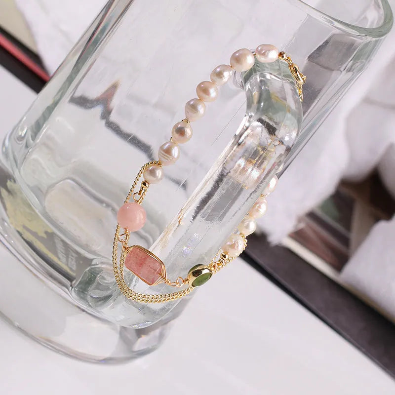 Close-up of a women's geometric bracelet with pink freshwater pearls and strawberry crystals on a wrist.