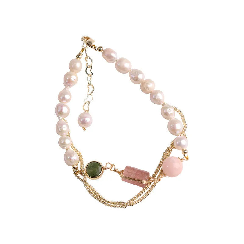 Close-up of a women's geometric bracelet with pink freshwater pearls and strawberry crystals on a wrist.