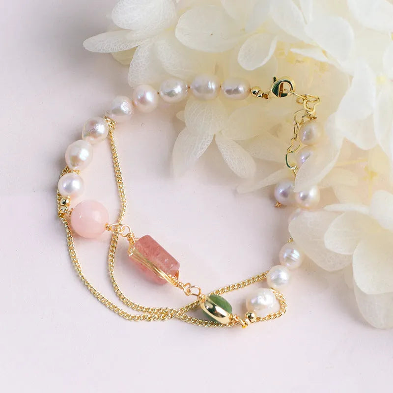 Close-up of a women's geometric bracelet with pink freshwater pearls and strawberry crystals on a wrist.