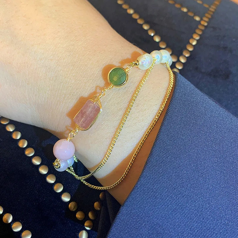 Close-up of a women's geometric bracelet with pink freshwater pearls and strawberry crystals on a wrist.