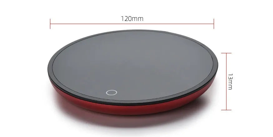 Black circular mug warmer with temperature switch, 12cm in diameter, on a desk next to a coffee cup.