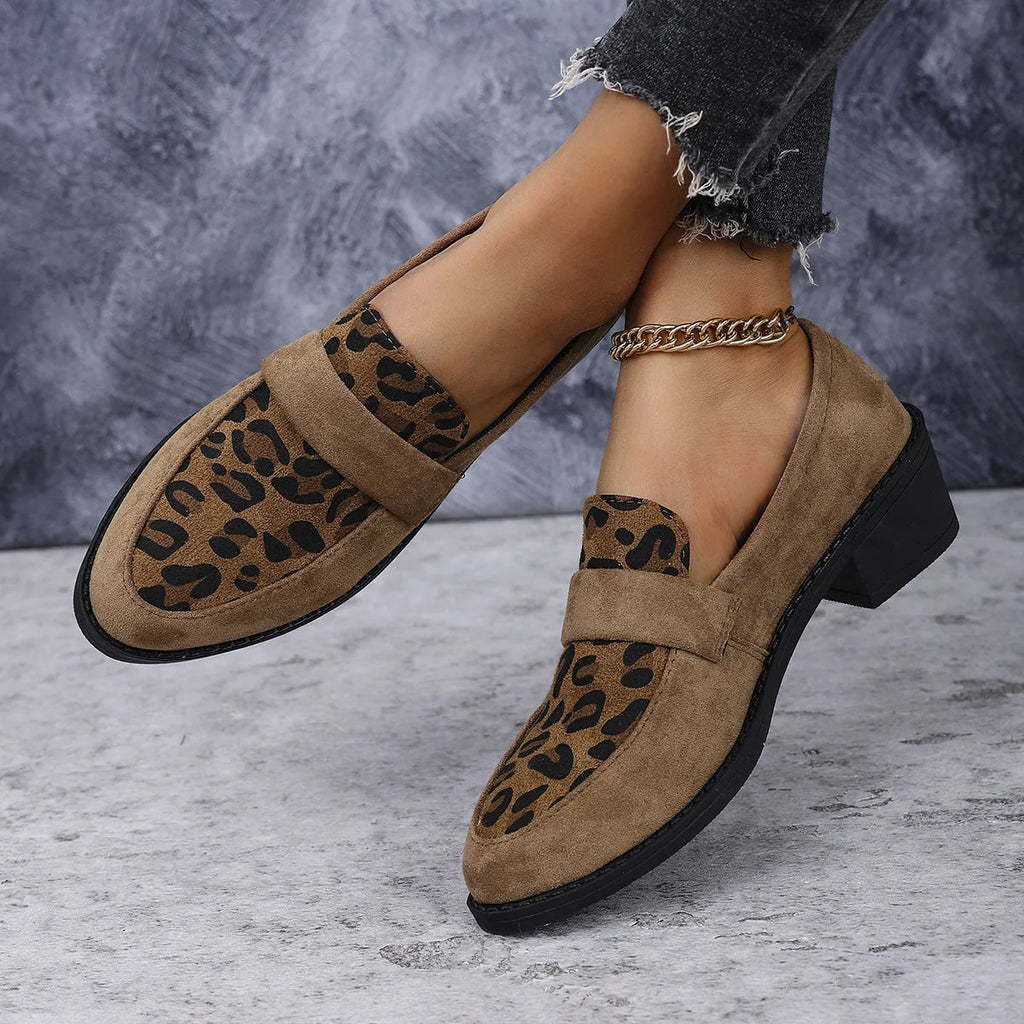 Women's leopard print suede slip-on shoe with a chunky mid heel and pointed toe on a brown background.