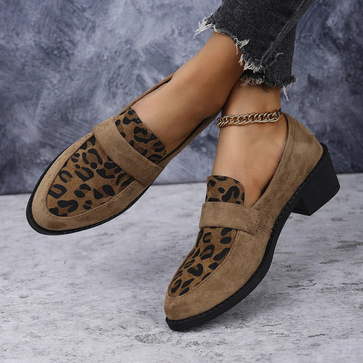 Women's leopard print suede slip-on shoe with a chunky mid heel and pointed toe on a brown background.