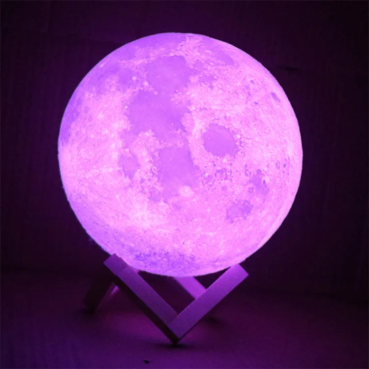 3D printed white moon lamp on a wooden stand with a glowing centre.