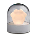 Grey cat paw shaped musical night light with USB charging cable on wooden desktop