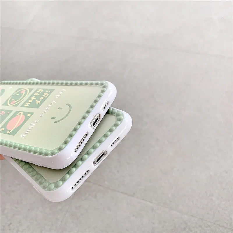 Green TPU iPhone case with geometric smiley face and polka dot design on a table.
