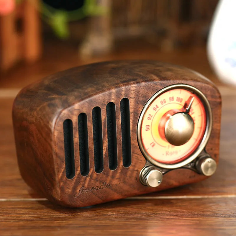 Retro wooden wireless mini speaker in cherry wood finish on a wooden table.