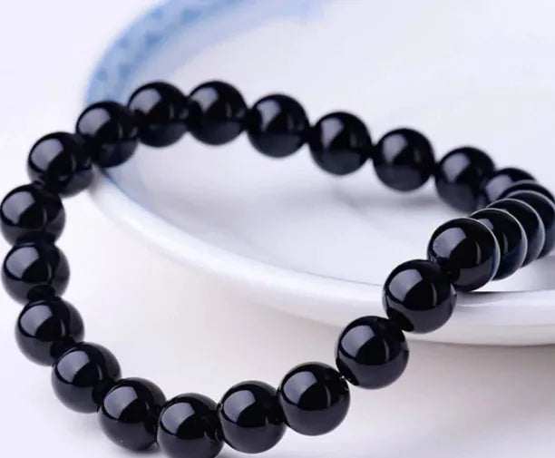 Women's black onyx agate beaded bracelet with geometric design and elastic cord.