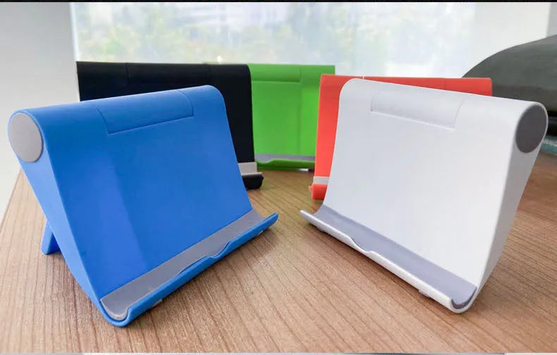 Black PE plastic folding phone stand holding a mobile phone at an angle on a wooden desk.