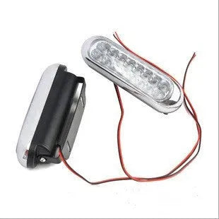 Two white car LED auxiliary lights with iron brackets and screws on a dark background