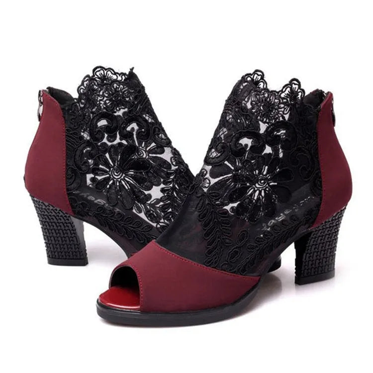 Black lace gladiator sandals with a square high heel, floral detail, and a zip closure at the ankle.