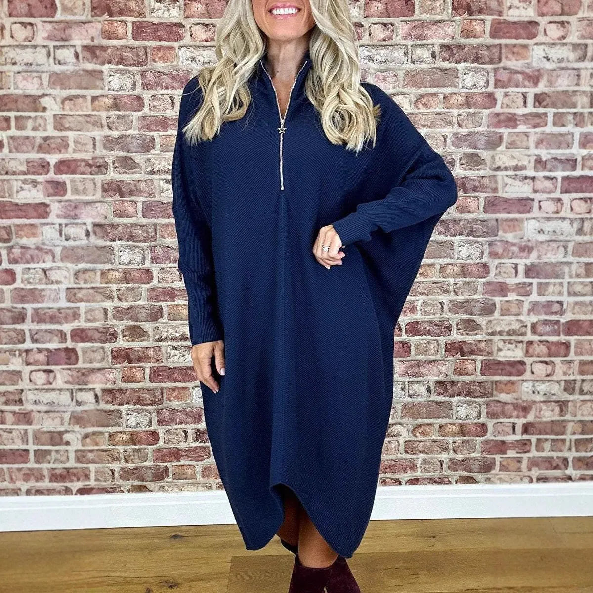 A woman wearing a solid colour loose knitted dress with raglan sleeves, shown in one of five available colours.