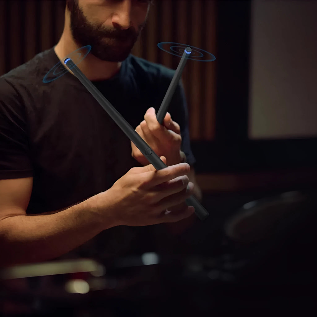 Black wireless air drum kit with two drumsticks, LED lighting, and USB-C charging cable