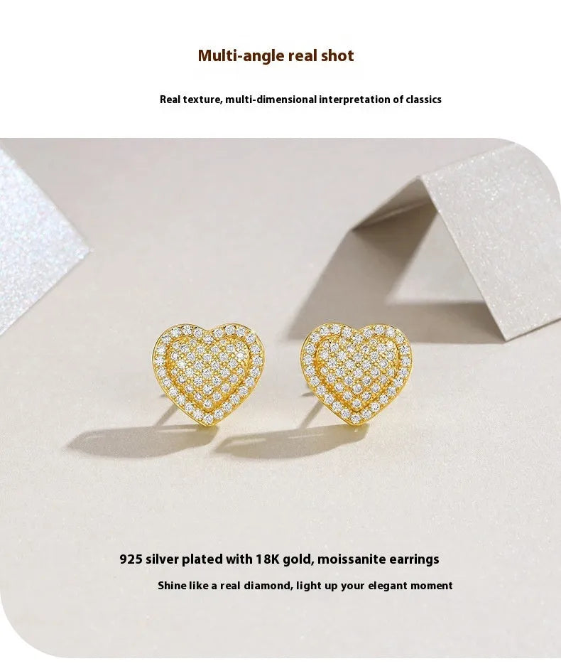 Golden heart-shaped stud earrings with moissanite centre on silver background
