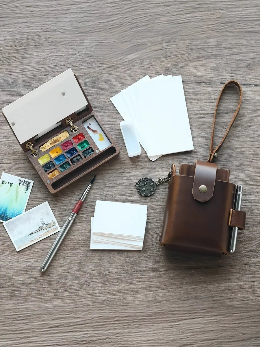 Miniature walnut wood watercolour paint box open to show 24 half-pan pigments and mixing areas