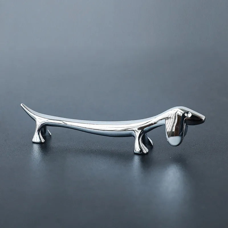 Silver zinc alloy sausage dog chopstick rest knife holder on desk with pen and chopsticks