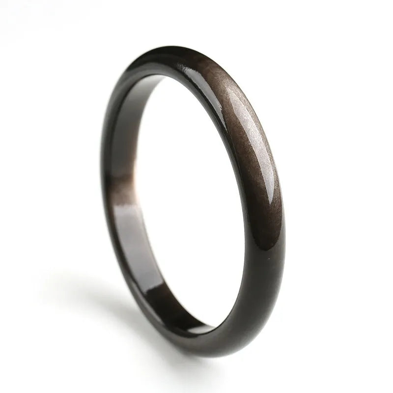 Black obsidian geometric ethnic bracelet with natural silver stone cat's eye design on a wrist.