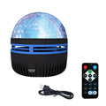 Compact LED galaxy projector night light with removable acrylic shade on a bedside table.
