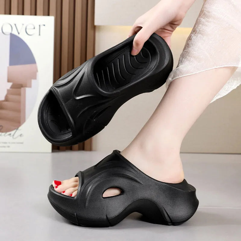 Women's white thick-soled EVA slippers with round toe on a sandy beach.