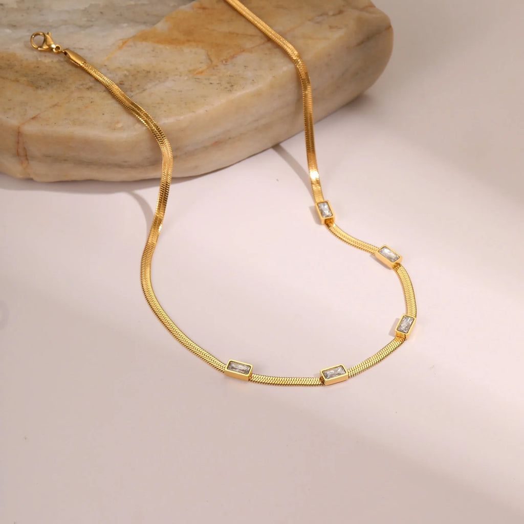 Gold geometric square zircon pendant on a stainless steel flat snake chain necklace.