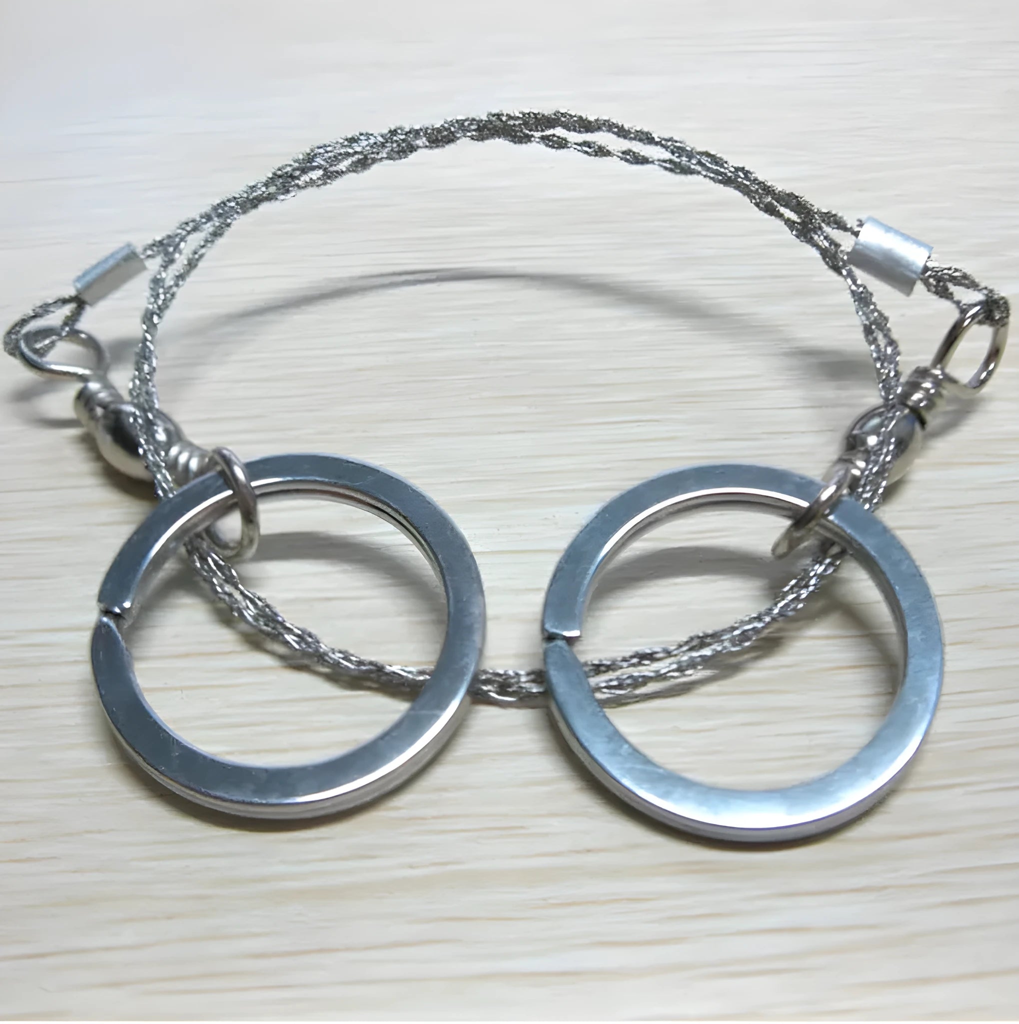 Stainless steel survival wire saw with thumb rings showing 55cm blade and compact storage size