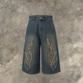Men's black cropped denim shorts with red and orange patch flame embroidery on the leg.